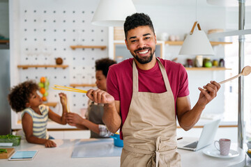 Happy african american family preparing healthy food in kitchen, having fun together on weekend