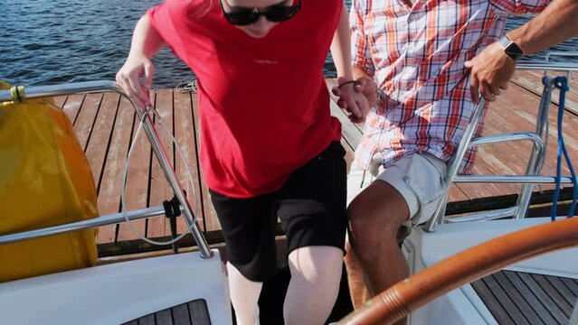 Friendly yachtsman gives welcoming hand to woman inviting on board. People prepare for yachting experience on summer weekend