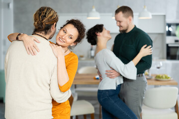 Two married couples dance during holiday, have fun, move and jump in dining room. Family event is held with fun music and dancing - obrazy, fototapety, plakaty