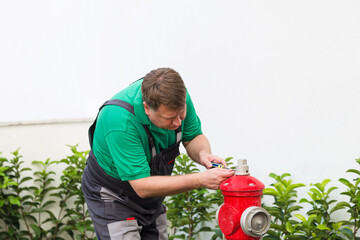Male worker repairing fire hydrant fire safety technical inspection.