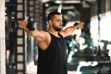 Portrait Of Motivated Young Man Training With Dumbbells At Gym - obrazy, fototapety, plakaty