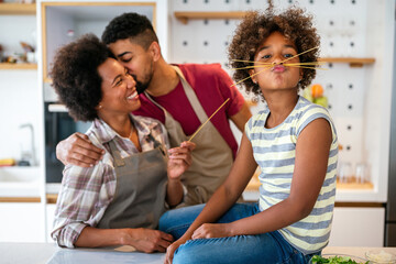 Overjoyed young african american family with kid have fun cooking at home together, - obrazy, fototapety, plakaty