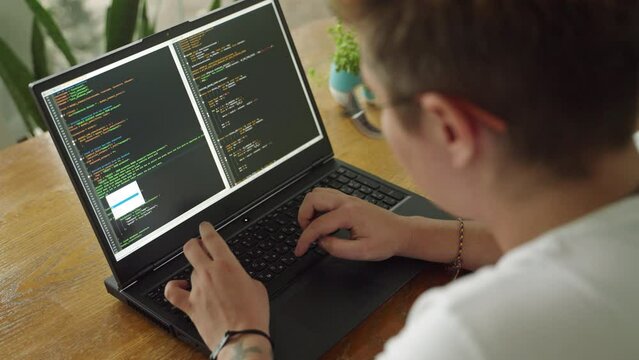 Transgender developer programs in modern coworking space. Inclusive work environment, gender diversity in tech industry, coding laptop. Pro focus on screen, innovation, collaboration. Slow motion.