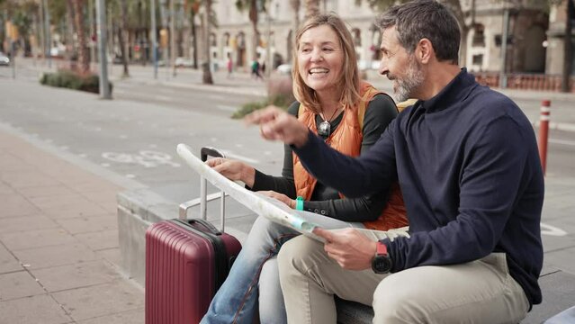 Adult tourist couple traveling together checking city map for landmark during weekend trip