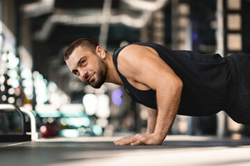 Bearded man holding plank position while training at gym