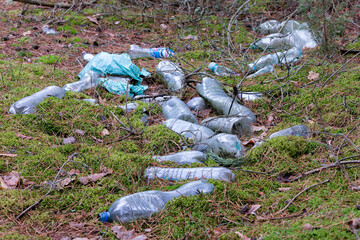 Illegal garbage dump of plastic and bottles in the forest. Humans mindlessly throw garbage into the...