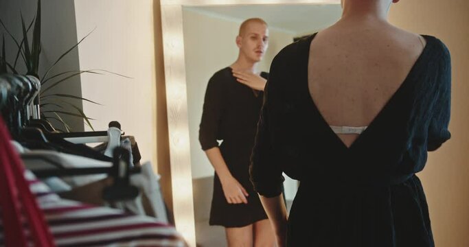 Trans in black dress enjoying his feminine image in mirror, proud homosexual