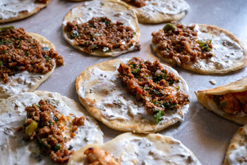Rolling out taco dough and filling it with foods such as chicken, meat and fish on the gray table	