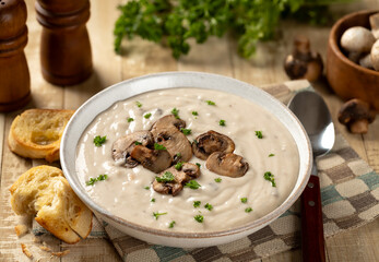 Bowl of creamy mushroom soup with sliced mushrooms and parsley