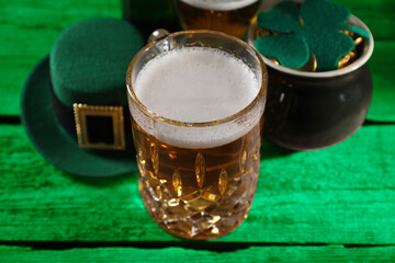 St. Patrick's day. Beer, leprechaun hat, pot of gold and decorative clover leaf on green wooden...