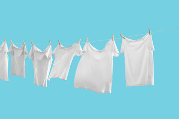 T-shirts drying on washing line against light blue background