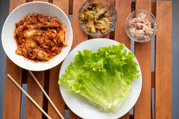 raising with various crops at the restaurant table, wrapping mushrooms and kimchee in cabbage