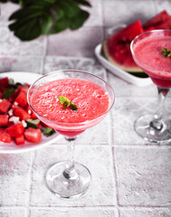 Watermelon refreshing summer frozen cocktail smoothie with watermelon slices and pieces on the background
