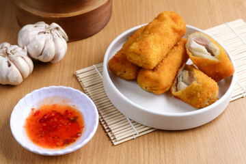 kue risoles mayo (risoles mayo cake) on wooden tray and penaut sauce served on table top. risoles mayo cake is one of popular indonesian foods.