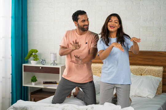 joyful energetic couples dancing together on bed after wakeup - concept of refreshment, carefree bonding and live in relationship