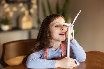 interested child learns how wind turbine works. concept of studying ecology and renewable energy sources