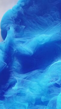 Vertical video. Smoke cloud background. Hypnotic explosion. Blue ink drop flow in water abstract mysterious ethereal liquid fume spreading on white.