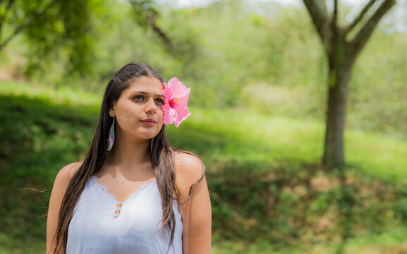 retrato de mujer latina al aire libre con cabello largo y una flor en su rostro
