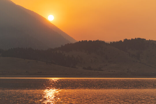 Sunrise colored gold by nearby wildfires, Eagle Nest State Lake Park, New Mexico