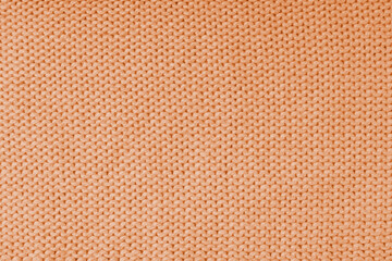 Close up background of knitted wool fabric made of viscose yarn, orange color wool knitwear texture. Sweater, pullover knitted jersey background. Fabric abstract backdrop, wallpaper