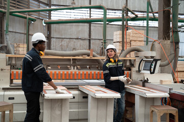 Male and female engineer control, maintenance and inspecting quality of machine in lumber storage factory. Warehouse and factory concept