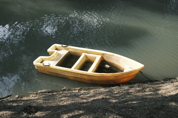 Old yellow plastic boat on the river