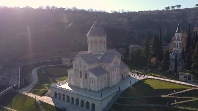 Scenic aerial view of monastic complex of Bodbe nunnery on hillside among tall Cypress trees with Church of St. Nino on sunny day, Sighnaghi, Georgia