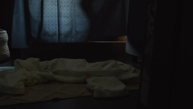 Medium close-up rear shot of legs and feet of young unrecognizable fair-skinned woman walking over bathroom mat, undressing, dropping white bathrobe on floor, stepping into shower and drawing curtain