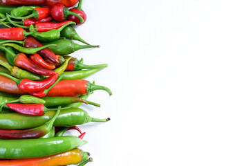 Pile of hot peppers border with space for text. Different green and red hot chili peppers frame isolated on white background