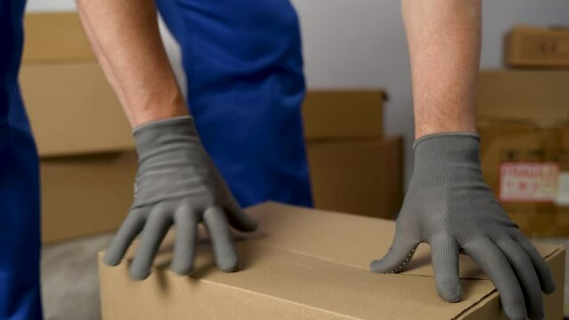 Worker sealing box with tape for moving, close-up