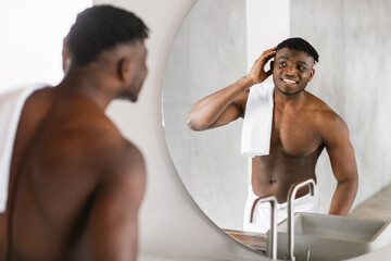 Handsome African American Man Smiles At Reflection In Bathroom Mirror