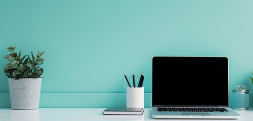 Laptop, documents, pencil holder on white table; vibrant teal backdrop in modern office.