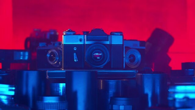Vintage camera with a set of lenses. The combination of classic design and bright red blue neon light creates an atmosphere of creativity, photo art. Close up.