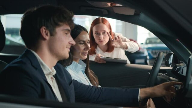 Happy husband and wife sitting inside new car choose luxury auto Caucasian woman saleswoman dealer help consult clients buyers family couple buying automobile in dealership purchase rent transport