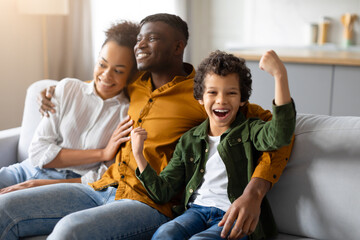 Black family with child boy celebrating victory, joyful moment together