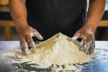 Baker's hands ready to knead a mound of flour, isolated on black background. prepares bread in the traditional way