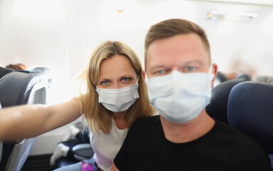Fototapeta na wymiar Family couple in protective masks on the plane, close-up. Protective measures against coronovirus during flight, vacation