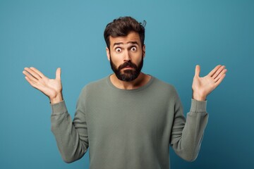 
What do you want? Portrait of annoyed frustrated bearded man standing with raised hands and indignant face asking why, annoyed by problem. Indoor studio shot isolated on blue background.