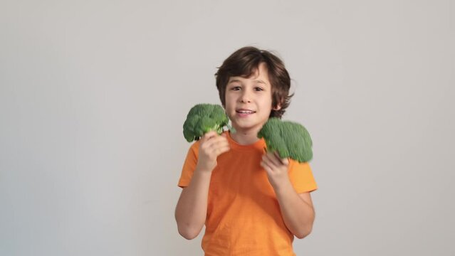 Hiding behind broccoli, the child's impish grin suggests a game of hide and seek, turning mealtime into an imaginative adventure.