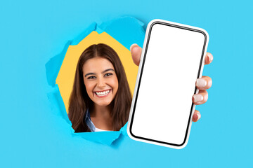 Happy woman holding cellphone in hand breaking through blue paper