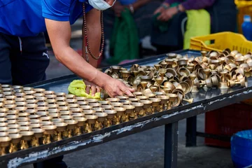Foto op Canvas Nepali temple staff pour out candle oil after wick burns out for replacement, cleaning bronze candle holders reuse, volunteer work in for Boudhanath Stupa temple in Kathmandu © TRAVELARIUM