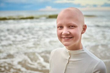 Close up portrait of smiling hairless girl with alopecia in white futuristic costume on sea background, bald pretty teenage girl showcasing unique beauty and identity with pride, unusual alien girl