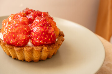 Strawberry tart on khaki green plate in restaurant with sun reflection
