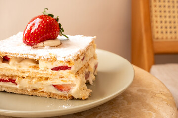 Strawberry tart on khaki green plate in restaurant with sun reflection
