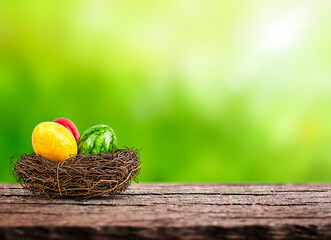 Colorful Easter eggs in a nest on wooden table on blurred natural background. Copy space