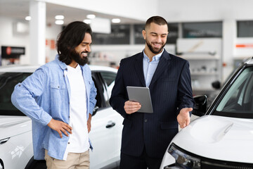 Indian guy standing by nice white car, talking to dealer