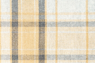 Close-up texture of tartan fabric in beige and gray colors at an angle. Concept of materials and...
