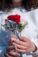 Handing flowers to boyfriend in white sweater on Valentine's Day in high noon sunlight
