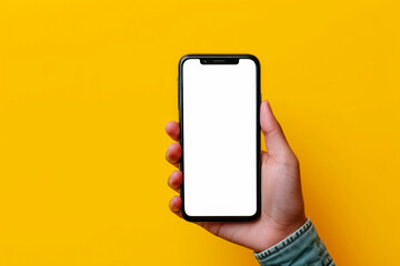 Hand holding the black smartphone with blank screen on yellow colour background.