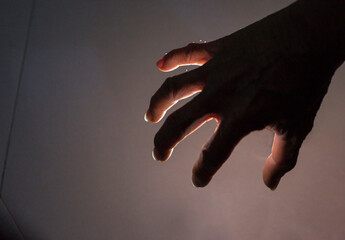 Hand and finger gestures perform magic on black background with light and shadow. Looks mysterious...